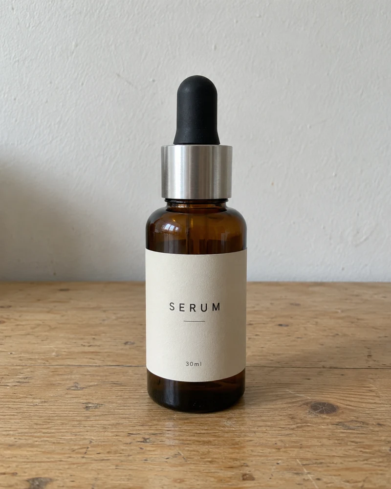 Botol serum di atas meja kayu kosong dengan cahaya biasa, simulasi raw shot.
